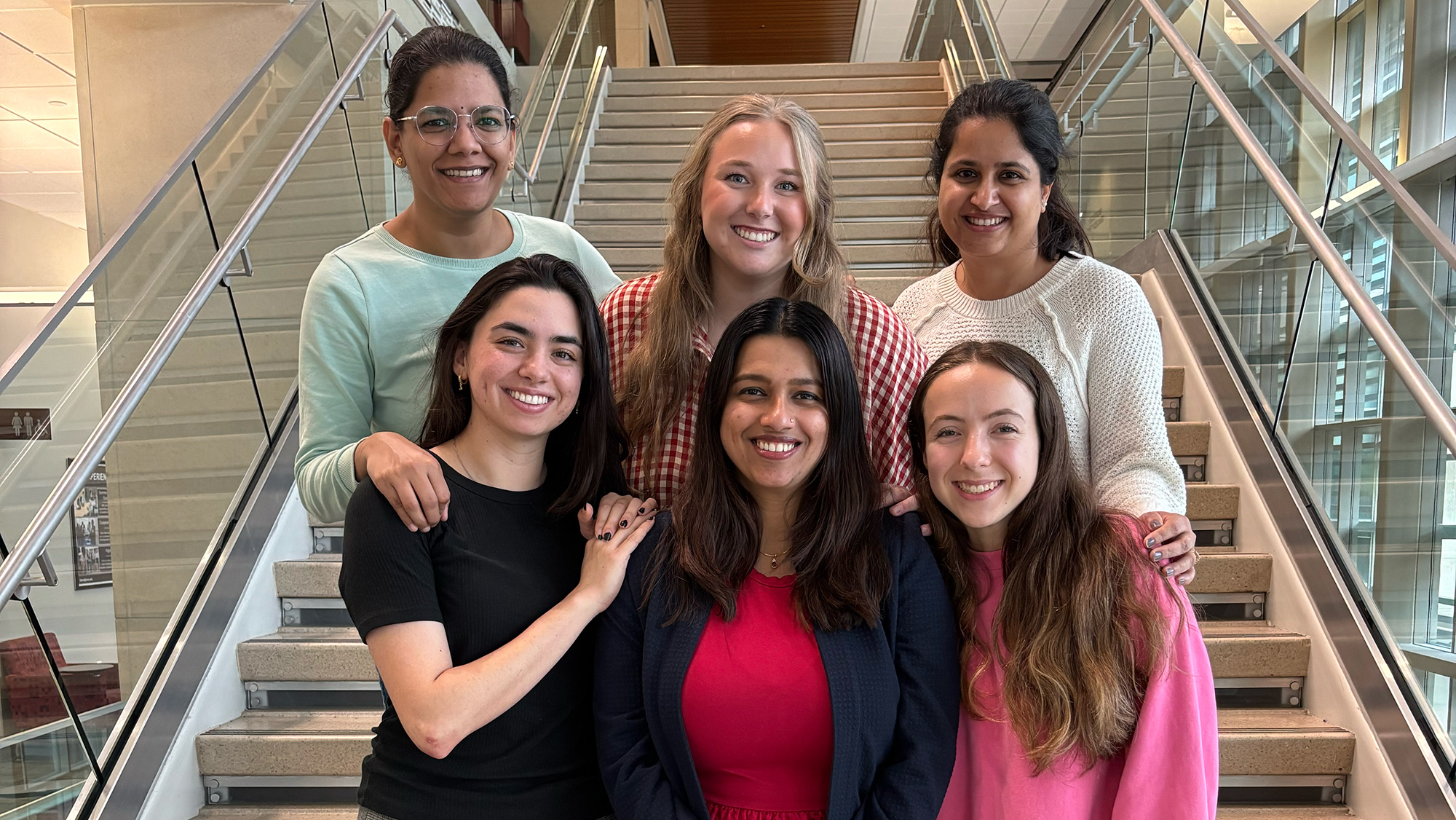 A group of six women poses for a photo on a large staircase.