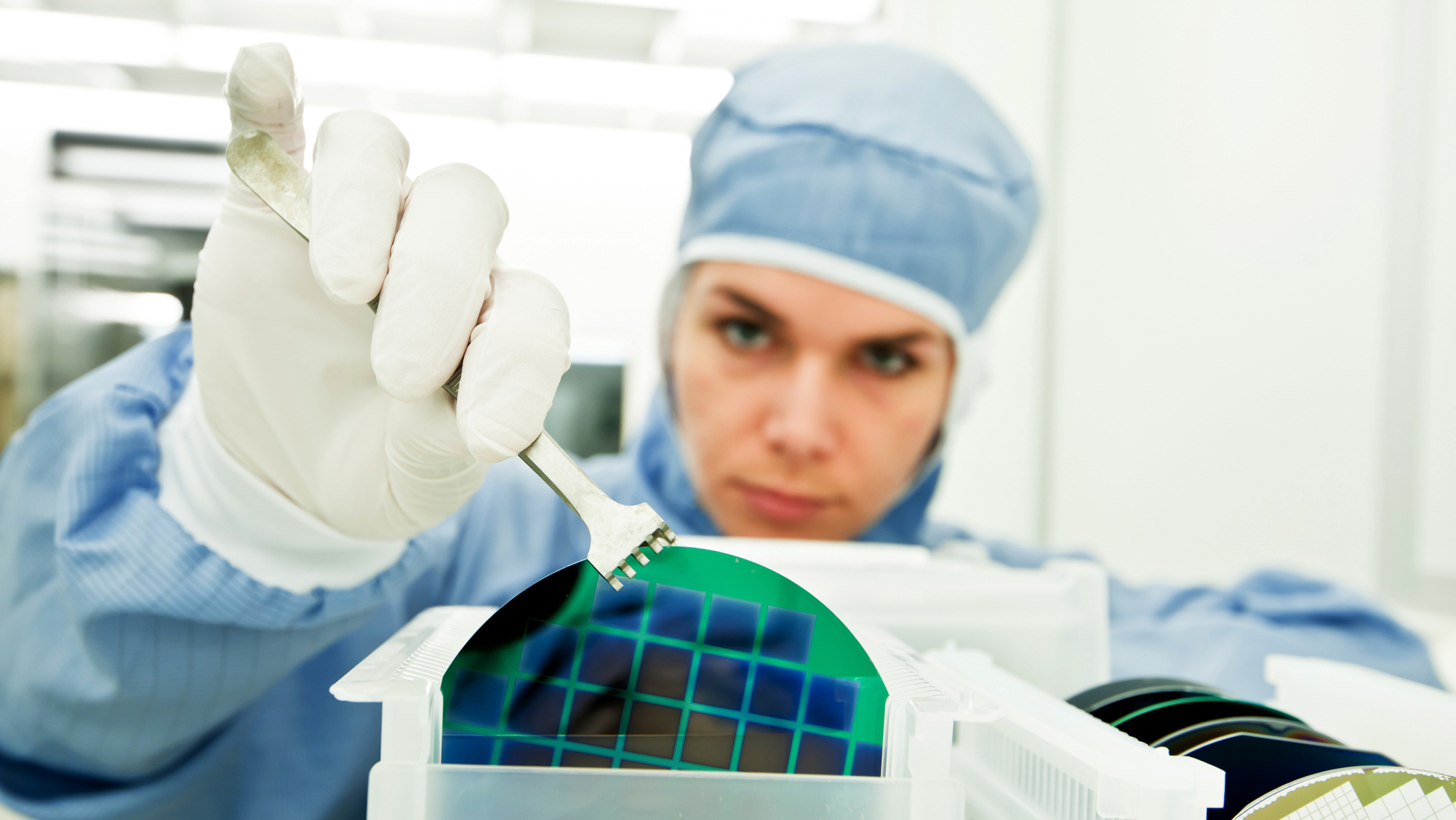 A woman in lab attire holding a lab material.