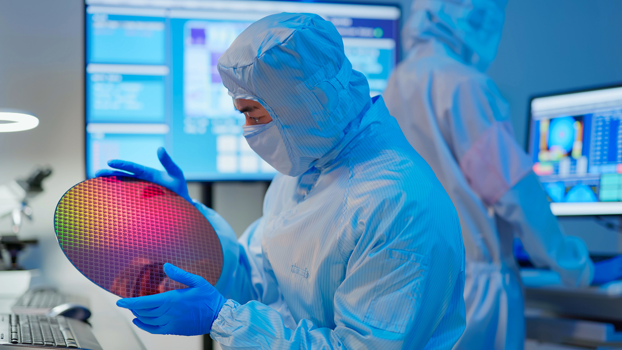 A person in a lab holds a semiconductor wafer.